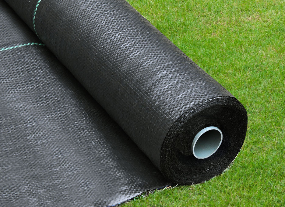 Roll of black weed barrier cloth on a grassy background